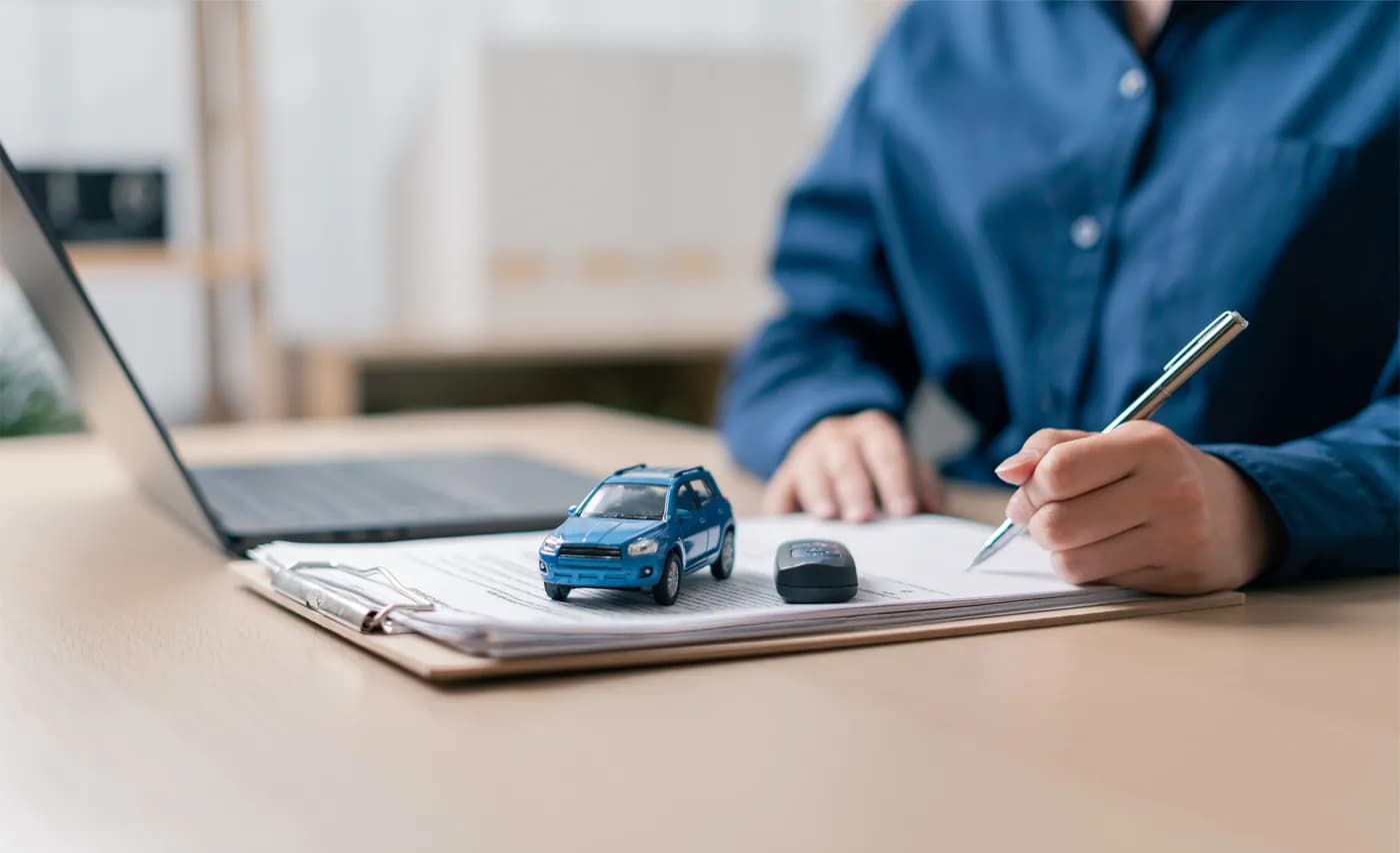 Vehicle seller working beside a laptop and vehicle paperwork before submitting an Oregon DMV sale notice online